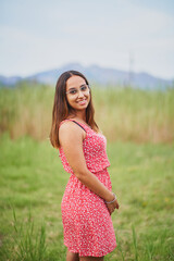 Fototapeta na wymiar Young spanish woman smiling at camera standing in idyllic green land
