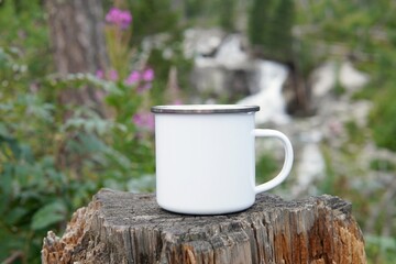 Blank enamel coffee cup mockup, empty camping mug in forest for design presentation, - obrazy, fototapety, plakaty