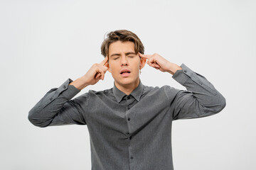 Tired or trying to rethink the information received while experiencing a headache young handsome man in grey shirt, look with cool hairstyle isolated on white background. 