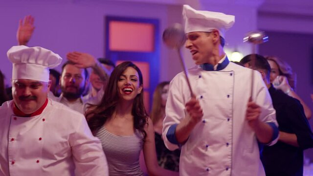 Cook dancers having fun dancing at a colorful party . Funny cook chef in white uniform, with a hat and ladle , smiling and partying during party . Shot on RED EPIC Cinema Camera in slow motion .