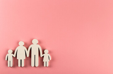 Wooden figurines of family on pink paper background.