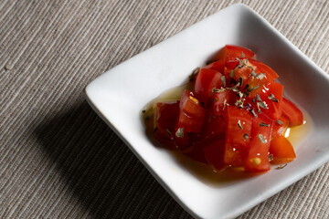 白い四角い皿に盛られたトマトのマリネ