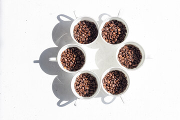 Roasted coffee beans in white cups on a white background
