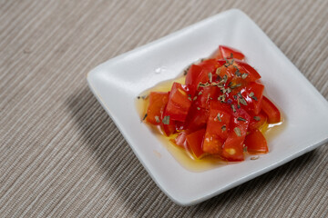 白い四角い皿に盛られたトマトのマリネ