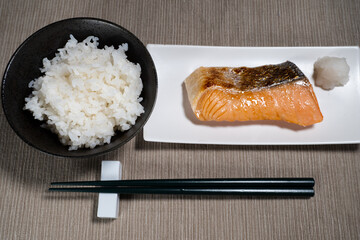 ご飯と白い皿に盛られた鮭の切り身