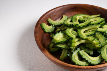 白い背景と木のボウルに盛り付けられたゴーヤの炒め物