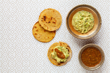 Avocado with tahini and greek yogurt sauce with roasted tomatillo salsa on corn roti flatbread.