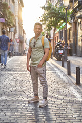 Fototapeta na wymiar Young smiling Latino man walking through the streets of the city. Latin man in jeans and green polo shirt. 