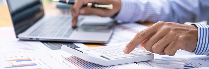 Accountant doing finance and calculate about cost on the desk at home office, close up hands of accountant using calculator count balance of the company.Calculating Bills With Calculator In Office