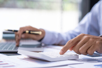 Accountant doing finance and calculate about cost on the desk at home office, close up hands of accountant using calculator count balance of the company.Calculating Bills With Calculator In Office