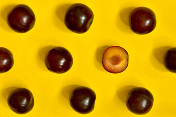 background with beautiful ripe plums on yellow. Summer cherry plum. Food pattern.