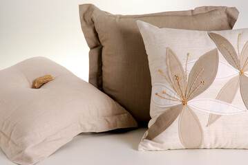 Three beige cushions. One of them has flowers pattern, isolated