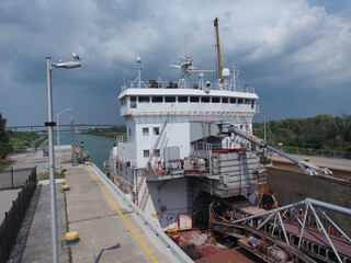 A long, narrow freight ship traverses the  Welland Canal that allows ships to bypass Niagara Falls...