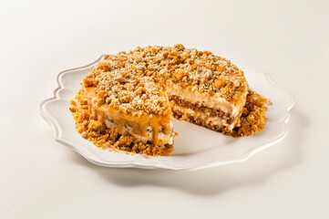 Dulce de leche and walnut layered cake on a plate, isolated