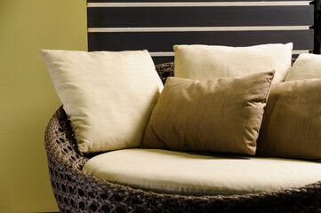 Detail of set of neutral colored pillows, on a rattan armchair