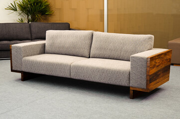 Modern gray couch with wood sides, set on a room with a beige wall