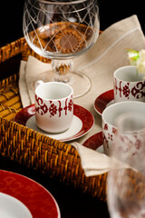 Detail of a straw tray with red and white tea cups and a cookie jar