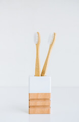 Bamboo toothbrushes in a wooden cup making with natural materials, isolated on white background