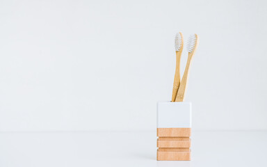 Bamboo toothbrushes in a wooden cup making with natural materials, isolated on white background with copy space. 