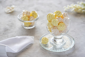 White and yellow meringue dessert in glass jar on a concrete table , side view