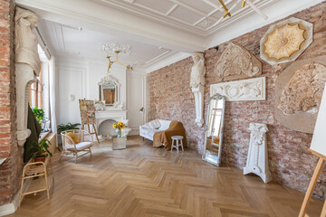 bright workshop room for the creation and work of an architect and artist in a loft style with brick walls and parquet. the walls are decorated with examples of stucco.