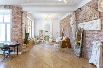bright workshop room for the creation and work of an architect and artist in a loft style with brick walls and parquet. the walls are decorated with examples of stucco.