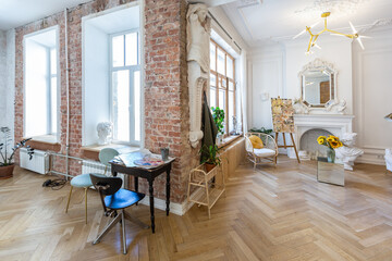 bright workshop room for the creation and work of an architect and artist in a loft style with brick walls and parquet. the walls are decorated with examples of stucco.