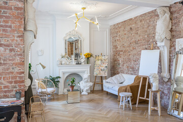 bright workshop room for the creation and work of an architect and artist in a loft style with brick walls and parquet. the walls are decorated with examples of stucco.
