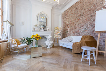 bright workshop room for the creation and work of an architect and artist in a loft style with brick walls and parquet. the walls are decorated with examples of stucco.