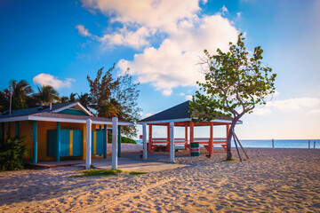 Colorful public toilet building and a wooden hut on Seven Mile Beach by the Caribbean Sea, Grand Cayman