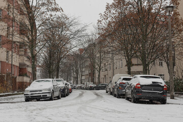 Parked cars in winter, cars covered with snow, snow-covered small street in Berlin Schöneweide, Germany