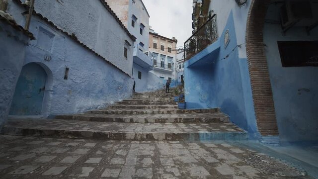 Forwards reveal of paved stairs in Chefchaouen. City is known with buildings in shades of blue. Morocco, Africa