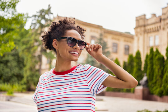 Photo portrait curly girl wearing sunglass striped t-shirt walking around college campus in summer