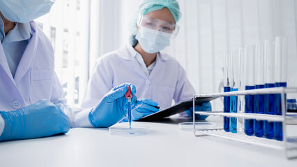 Medical or scientific researcher or man doctor looking at a test tube of clear solution in a laboratory