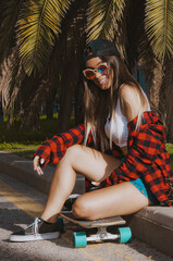 latin girl in cap and sportswear looks at you and smiles. Young woman poses sitting on the sidewalk...