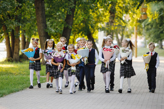 Girls And Boys In School Uniforms With Flowers.