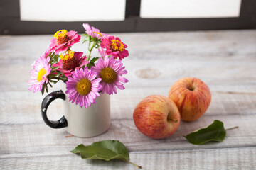 Still life with apples and flowers on a wooden surface by the window