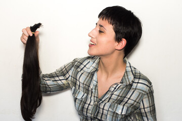 Mujer joven con pelo corto sosteniendo su cabello cortado en una cola de caballo. Concepto de...