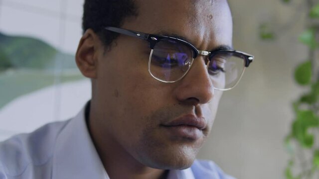 African american man hacker in eyeglasses trying to crack system with laptop