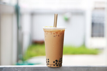 big cup iced milk tea wih bubble boba fresh and sweet drink Taiwan style put on the steel bar and blur background , food and drink concept