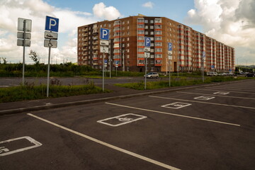 Parking spaces for disabled people with road signs, demarcated on the asphalt, in the background of a residential building.