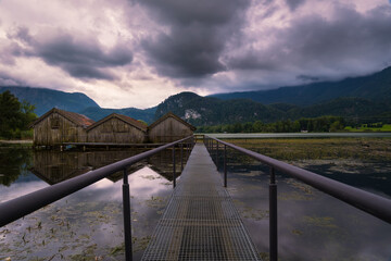 View on boat houses at lake Kochelsee on cloudy summer day, vanishing point perspective