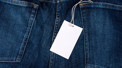 Empty white price tag with blank space for mockup on blue jeans