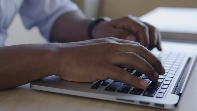 Close-up black male hands quickly typing on laptop, writer working on new book