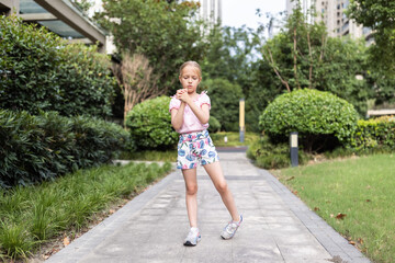 Fototapeta na wymiar Cute little caucasian Girl with blonde hair Stretching outdoor on backyard Before Running