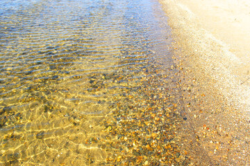 Clean sea water and stones at the bottom. Rocky seashore. Pebbles and rocks underwater underwater.Close-up and top view of shiny transparent yellow sand and stones on the beach with clear water. clear