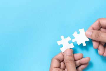 Hand push a piece of jigsaw puzzle to complete the mission for business merging concept or coorperate acquisition