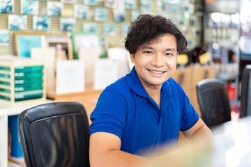 Happy Asian male office worker working with computer desktop in the auto car repair shop. Receptionist male in the office. Male office worker. Asian male staff. Car service concept