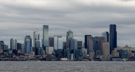 Fototapeta premium Seattle Skyline from Elliott Bay takes on a silvery sheen from sun coming through the overcast clouds.