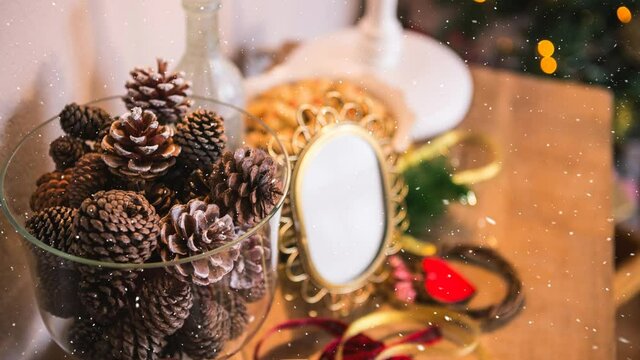 Snow falling over multiple pine cones in a glass bowl on wooden table